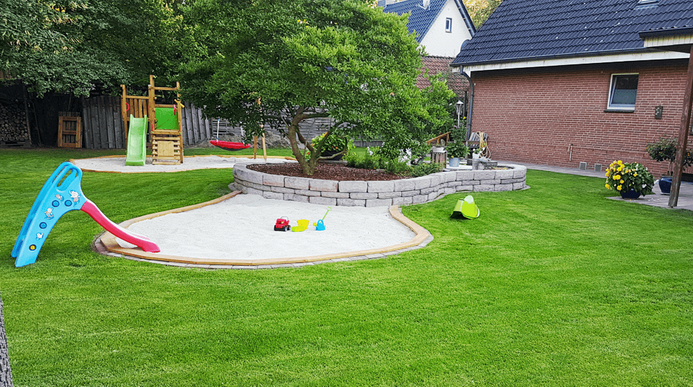 Großer Garten mit Terrasse, Sandkasten und vielfältigen Spielmöglichkeiten für Kleinkinder in naturnaher Umgebung
