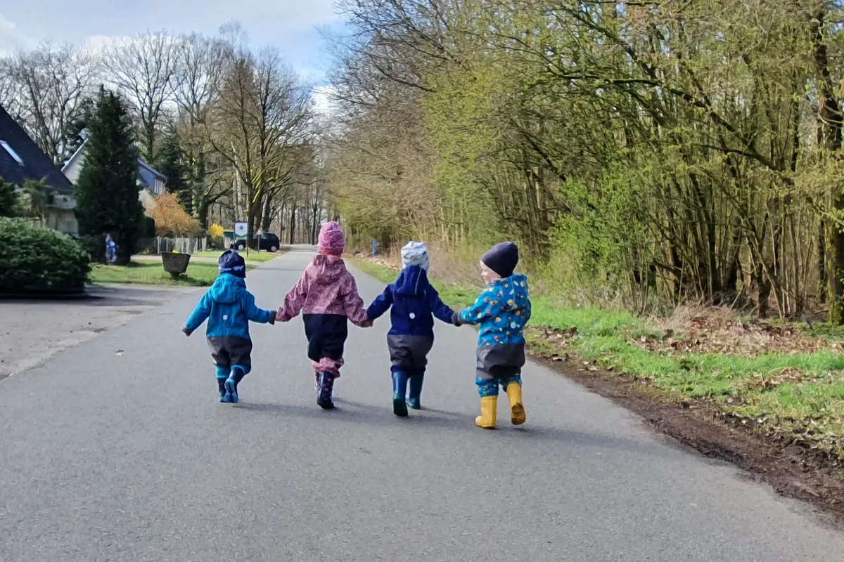 Vier Kinder halten Hände bei einem Spaziergang in die Natur